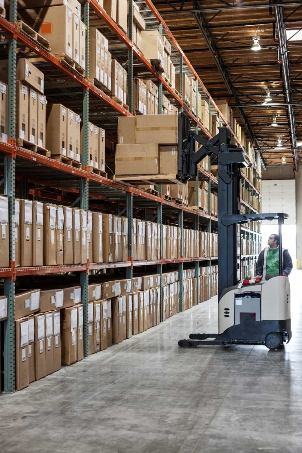 Employee picking products off warehouse racks with a forklift